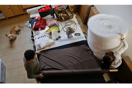 El mestizo Akita-Labrador ''Willy'' se relaja mientras los empleados Marina, derecha, y Alfredo trabajan en la sede de la fábrica Temellini