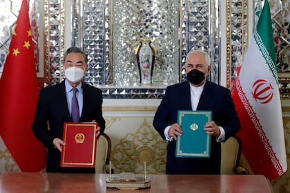 El ministro de Relaciones Exteriores iraní, Mohammad Javad Zarif y su homólogo chino Wang Yi, posan para una foto después de firmar un acuerdo en la capital, Teherán, el 27 de marzo de 2021