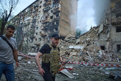 El ministro del Interior de Ucrania, Ihor Klymenko, derecha, recorre el sitio donde cayó un misil que destruyó un edificio residencial durante un ataque aéreo masivo con drones y misiles de Rusia en Kiev, Ucrania, el martes 17 de junio de 2025.