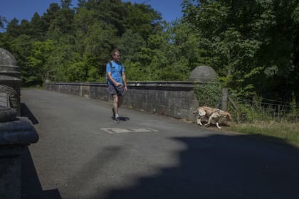 Un hombre lleva su perro con correa sobre el misterioso puente Overtoun en Dumbarton, Escocia