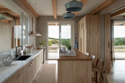 El mobiliario en kiri al natural acompaña la materialidad rústica del resto de la casa. Grifería (Peirano).