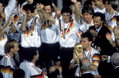 El momento cumbre: como capitán de Alemania, Matthäus recibe la Copa del Mundo en Italia 90, con Beckenbauer detrás; abajo, a la izquierda, Brehme, el hombre del penal