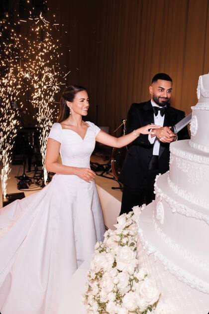 El momento del
primer corte de la torta
de bodas, decorada con
flores blancas.