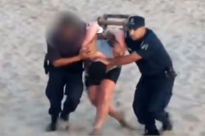 El momento en que el hombre es trasladado por la policía de la playa al patrullero