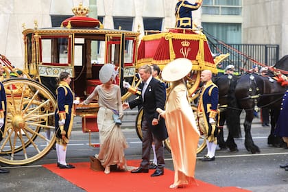 El monarca ayuda a su mujer a bajar de la Carroza de Cristal, ante la mirada de la heredera del trono de los Países Bajos