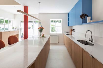 El mueble de cocina diseñado por Bouré combina melamina ‘Roble Kendal Natural’ (Egger) y secciones laqueadas en azul Dyer’s Woad 9071 de Sherwin Williams. Las mesadas (Ital Piedras) son de Purastone ‘Terrazzo White’ en la barra y Silestone ‘Blanco Norte’ donde se alojan la pileta y el anafe.