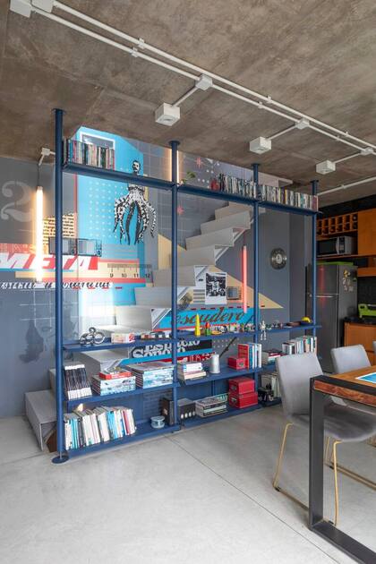 El mural de Cabaio Spirito convive con la biblioteca de chapa azul petróleo. Tubos de led suspendidos (Huup) acompañan el recorrido y permiten iluminar la casa con una sola tecla.