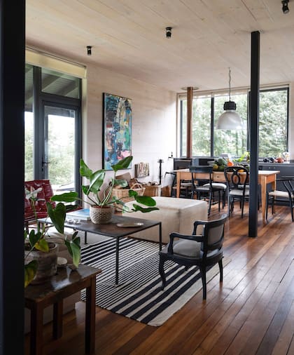 El negro de la perfilería metálica se replica en la estructura del mobiliario, como los respaldos de las sillas elegidas para el comedor y el living.