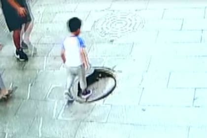 El niño pisa la tapa floja de la alcantarilla sin saber el peligro que lo espera