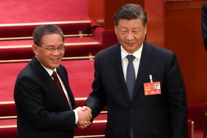 El nuevo primer ministro electo de China, Li Qiang, a la izquierda, estrecha la mano al presidente chino Xi Jinping