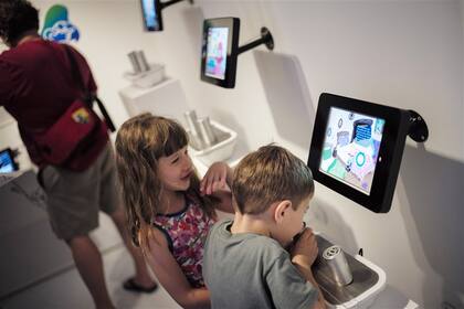 Chicos que siguen una historia en un dispositivo con fragancias, en un museo de Nueva York