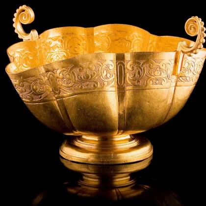 El ornamentado cáliz de dos asas está adornado con volutas grabadas en la parte superior