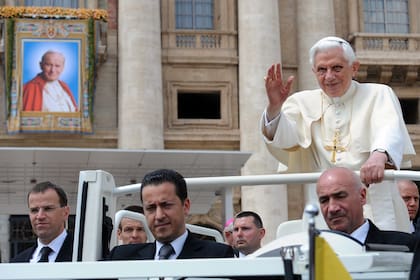 El papa Benedicto XVI saluda mientras está parado en su papamóvil con su mayordomo Paolo Gabriele, al llegar a una audiencia general, el 4 de mayo de 2011 en la plaza de San Pedro en el Vaticano