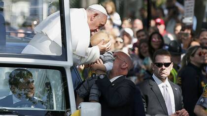 El Papa besa a un bebe durante su recorrido con el papamóvil
