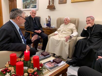 El papa emérito Benedicto XVI se reúne con los ganadores del Premio Ratzinger 2022, Joseph Halevi Horowitz Weiler, a la izquierda, y el padre Michel Fedou, parcialmente oculto a la derecha, en el monasterio Mater Ecclesiae dentro del Vaticano donde vive Benedicto XVI, el jueves 1 de diciembre de 2022. El segundo desde la izquierda es el presidente de la fundación, el padre Federico Lombardi, y el cuarto desde la izquierda es el obispo Georg Gänswein, secretario personal de Benedicto XVI durante mucho tiempo. (Foto, Fundación Vaticana J. Ratzinger vía AP)