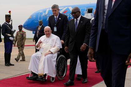 El Papa Francisco en silla de ruedas es flanqueado por el Primer Ministro congoleño Sama Lukonde, en el centro a la derecha, a su llegada a Kinshasa, República Democrática del Congo, el martes 31 de enero de 2023