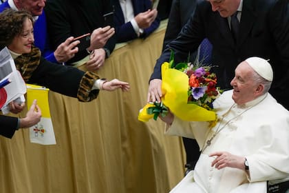 El papa Francisco recibe flores durante la audiencia general semanal en el Aula Pablo VI en el Vaticano, 15 de febrero de 2023. (AP Foto/Alessandra Tarantino)