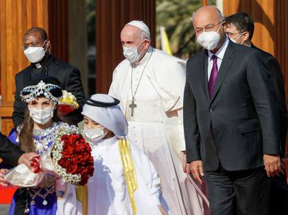 El Papa Francisco y el presidente iraquí Barham Salih, acompañados por niños que traen flores cuando se reúnen en el Palacio Presidencial de Bagdad