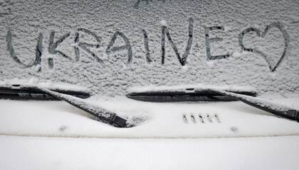 El parabrisas de un auto en Kiev, con la primera nevada de la temporada y un corazón junto al nombre del país
