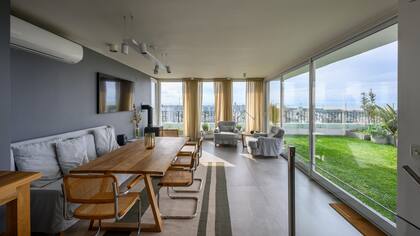 El parque de césped natural, un respiro en medio de la ciudad. Equipararon los tonos de la pared (Sinteplast) y la funda del sillón, y sumaron sillas 'Cesca' con asiento y respaldo de esterilla (Siuk Objetos).