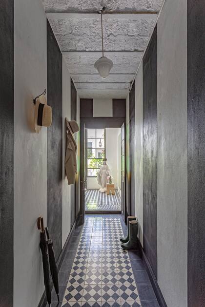 El pasillo de la casona de 1923 de la diseñadora Carolina Aubele en Belgrano R, conserva su buen estado y en su pasillo destacan las paredes en blanco y negro y un piso con cerámicos.