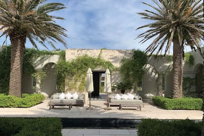 El patio interno, protegido de los vientos, es el corazón de la casa. Se repiten las palmeras que dan carácter y escoltan el estanque-pileta de 20 metros de largo, cuyo interior fue revestido en parte en laja negra, que le da profundidad.