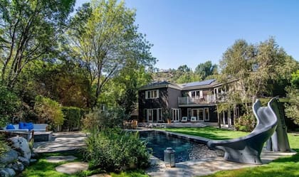 El patio trasero de la mansión cuenta con una piscina con tobogán (MLS.com)