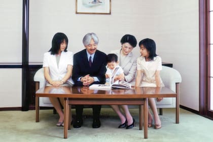 El pequeño príncipe con un libro, sentado en la falda de su mamá, la princesa Kiko, y junto a su papá, el príncipe Akishino, y sus hermanas, Mako (a la izquierda) y Kako (a la derecha), en 2007.