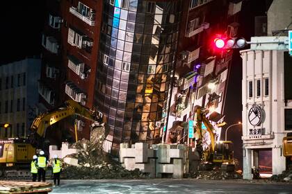 El personal de emergencia se encuentra frente a un edificio parcialmente derrumbado que se inclina sobre una calle en Hualien el 3 de abril de 2024, después de que un gran terremoto azotara el este de Taiwán.