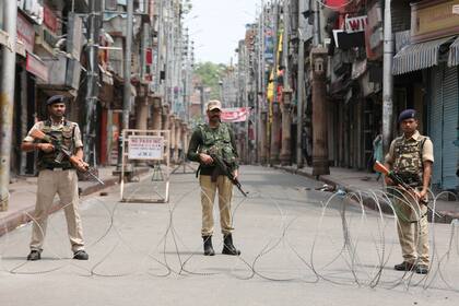 El personal de seguridad indio hace guardia en una calle desierta durante el toque de queda en Jammu
