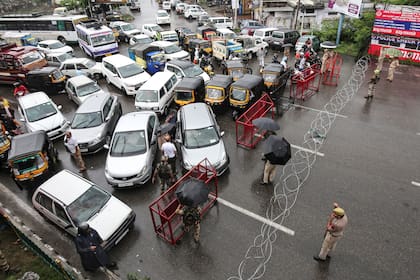 El personal de seguridad indio vigila mientras detienen el tráfico durante el bloqueo en Jammu