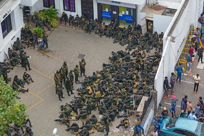 El personal del ejército se sienta cerca de los manifestantes (que no se ven) exigiendo la renuncia del presidente de Sri Lanka, Gotabaya Rajapaksa, reunidos dentro del recinto del Palacio Presidencial de Sri Lanka en Colombo el 9 de julio de 2022