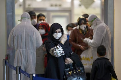 El personal médico distribuye hojas de información a los pasajeros iraquíes que regresan de Irán al aeropuerto internacional de Najaf el 5 de marzo de 2020