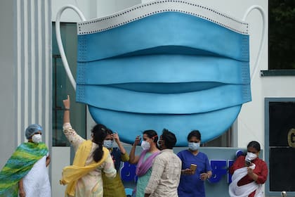 El personal médico toma fotografías junto a una gran réplica de una mascarilla que se muestra como una campaña de concientización contra el coronavirus, en Chennai, la India, el 1 de enero de 2021