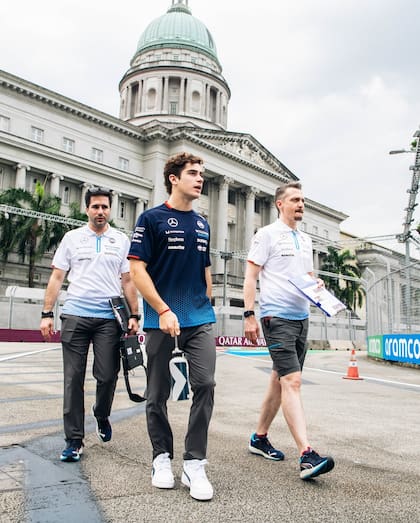 El piloto argentino camina por el circuito callejero de Marina Bay, Singapur; a su izquierda, el francés Gaëtan Jego, el ingeniero que lo guía mediante la radio en cada gran premio.