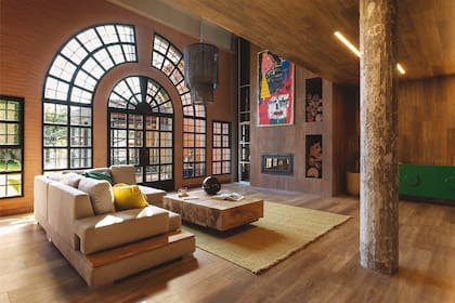 El piso ‘Fusion Fibrex Honey’ (Patagonia Flooring) se eleva hasta las paredes para dar un efecto homogéneo y dinámico. Donde estaba la chimenea construyeron un nuevo hogar (Tromen) con frente de porcelanato símil óxido ‘Piú Hander’ (Cerámica Piú) y nichos para la leña.