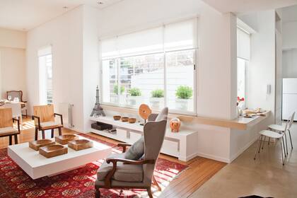 El piso se hizo con de pino tea reciclada de los antiguos dormitorios. La alfombra persa delimita el área del living. Sobre el mueble bajo de madera laqueada, Torre Eiffel de hierro forjado y chanchos de barro traídos del Norte.