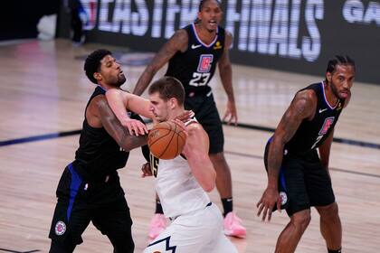 El pívot de los Denver Nuggets Nikola Jokic (15) impulsa contra el escolta de Los Angeles Clippers Paul George (13) durante la segunda mitad de un partido de baloncesto de semifinales de la conferencia de la NBA el martes 15 de septiembre de 2020 en Lake Buena Vista