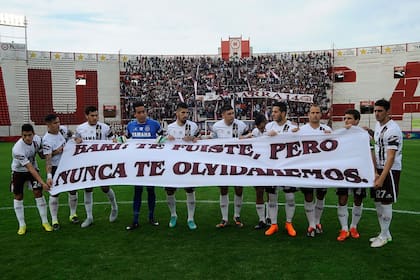 El plantel de Lanús y la bandera en homenaje a Barisone