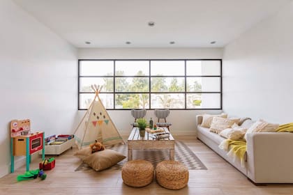 El playroom tiene cocinita (Casa Ideas), carpa (Futi Tiendas de Campamento), alfombra (HM Home), pufs de mimbre (Sol Palou) y sofá con almohadones de tussor con pasamanería (Vero B, Home Deco) y manta color limón (Cuatro Elementos).