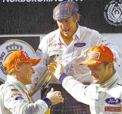 Jackie Stewart, junto con los pilotos Johnny Herbert y Rubens Barrichello en el podio del Gran Premio de Europa 1999, en Nürburgring; el único éxito de la escudería Stewart, que luego se convirtió en Jaguar para ser vendida en 2004 a Red Bull Racing