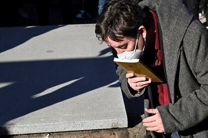 El poeta y director del Instituto Cervantes Luis García Montero besa la tapa de un ejemplar de "Completamente viernes" en la despedida de su mujer, Almudena Grandes