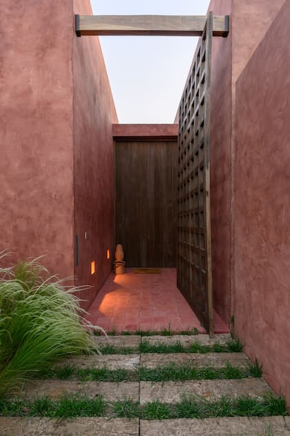 El portón de ingreso en madera maciza de kiri reproduce el patrón cuadriculado de la fachada