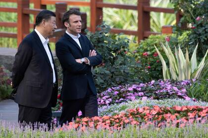 El presidente chino Xi Jinping y su par francés Emmanuel Macron visitan el jardín de la residencia del gobernador de Guangdong, el 7 de abril de 2023.