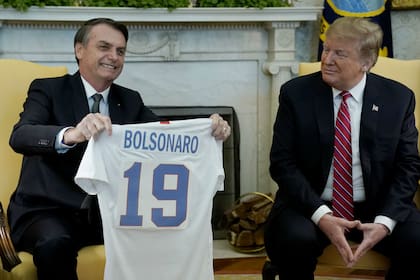 El presidente de Brasil, Jair Bolsonaro, recibe una camiseta de fútbol de los Estados Unidos del presidente Donald Trump, antes de una reunión en la Oficina Oval de la Casa Blanca