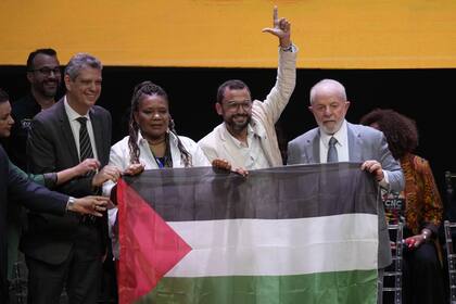 El presidente de Brasil Luiz Inacio Lula da Silva agarra una bandera de Palestina junto al poeta Antonio Marinho, la ministra de Culture Margareth Meneses, y el secretario general de la presidencia Marcio Macedo