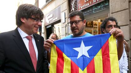 El presidente de Cataluña, Carles Puigdemont, en Barcelona, con un simpatizante de la independencia
