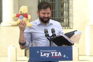 El presidente de Chile, Gabriel Boric, sostiene un peluche de Winnie de Pooh que le regaló un asistente