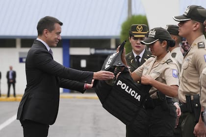 El presidente de Ecuador, Daniel Noboa, entrega un chaleco antibalas a un oficial de policía durante una ceremonia de entrega de equipo a la policía, en la Gral. Escuela de policía Alberto Enríquez Gallo en Quito, Ecuador, lunes 22 de enero de 2024.