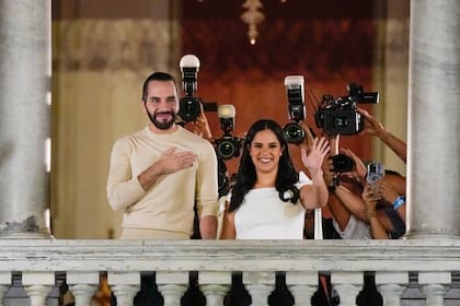 El presidente de El Salvador, Nayib Bukele, izquierda, acompañado por su esposa Gabriela Rodríguez, saluda a sus seguidores desde el balcón del palacio presidencial en San Salvador, después del cierre de las urnas para las elecciones generales del domingo 4 de febrero de 2024